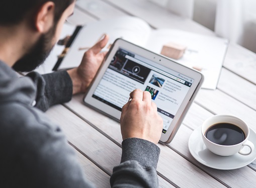 man reading from tablet next to coffee